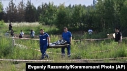 Angajați ai sistemului judiciar din Rusia ridicând corpul neînsuflețit al fostului ministru al Transporturilor, dintr-o zonă împădurită. El a fost descoperit mort în urma unei răni provocate prin împușcare, la câteva ore după ce a fost demis de V. Putin.