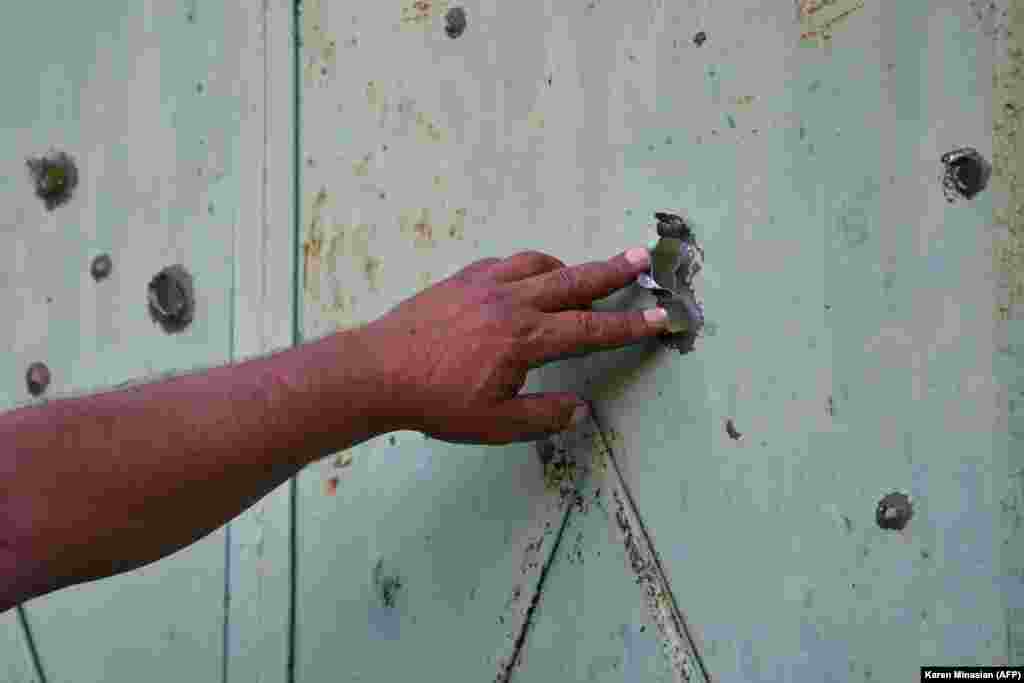 Stanovnik armenskog sela Aygepar pokazuje vrata oštećena granatiranjem 15. jula.