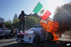 Протестующий стоит на горящем автомобиле, Лос-Анджелес, 8 июня 2025 года