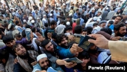 Afghan men wait to collect tokens needed to apply for Pakistan visas in Jalalabad on October 21.