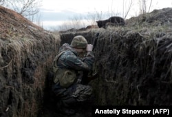 Mačka gleda u ukrajinskog vojnika koji se u februaru odmarao u rovu na prvoj borbenoj liniji sa separatistima koje podržava Rusija, u blizini sela Krasnohorivka.