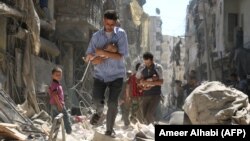 Чоловіки несуть на руках немовлят розгромленим війною містом Алеппо на півночі Сирії, 11 вересня 2016 року