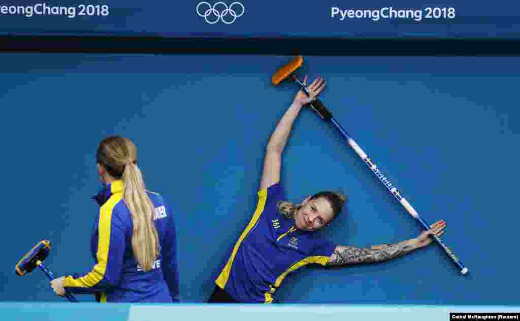 Керлінг: Агнес Кнохенхауер і Софія Мабергс зі Швеції розтягуються перед тренувальної сесією на льодовому катку в Каннині під час зимових Олімпійських ігор в Пхьончхані