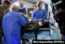 სცენარის მიხედვით ქართველი და ამერიკელი ექიმები დაჭრილს უკეთებენ ოპერაციას.