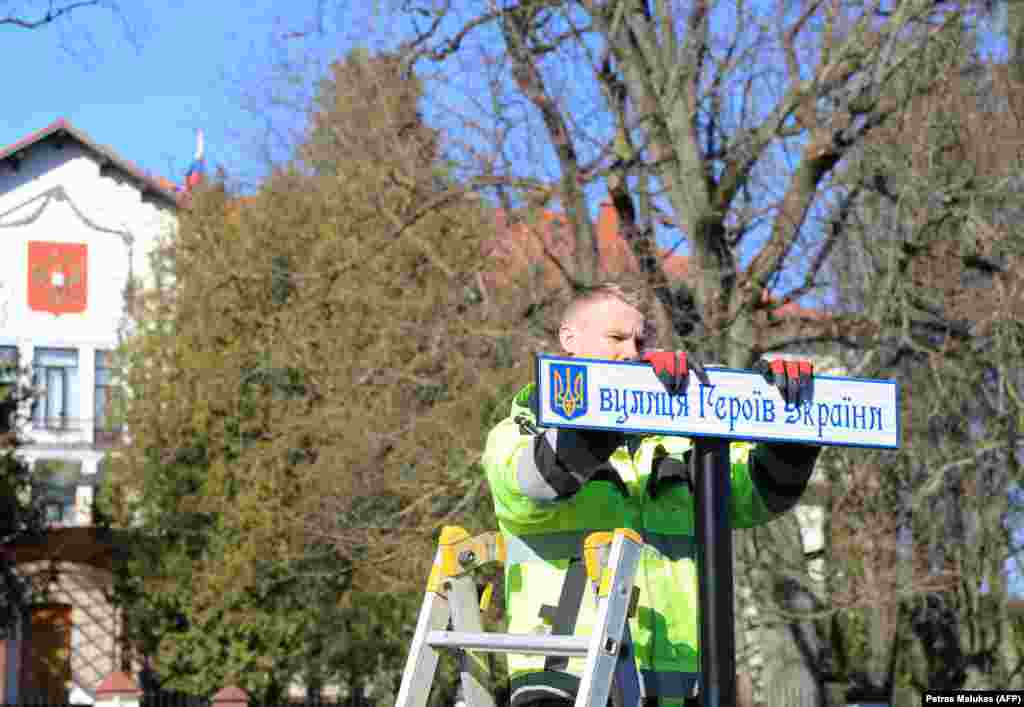 Рабочий устанавливает дорожный знак на украинском языке после переименования дороги, ведущей к посольству России в Вильнюсе в улицу Украинских Героев.