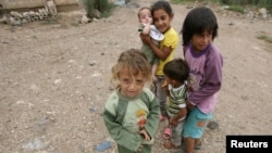 Syrian refugee children, who fled the violence, stand on a road at a northern Lebanese border village