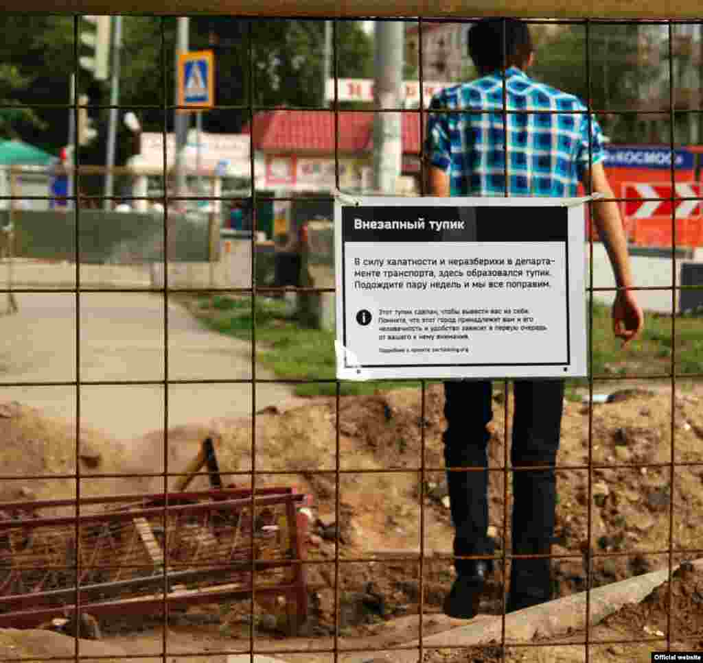 Акція «Партизанінгу». Текст на табличці: «Через халатність та безлад в департаменті транспорту тут з’явився глухий кут. Зачекайте кілька тижнів і ми все виправимо. Цей глухий кут тут для того, щоб вивести вас із себе. Пам’ятайте, що це місто належить вам і його людяність та зручність залежить в першу чергу від вашої уваги».