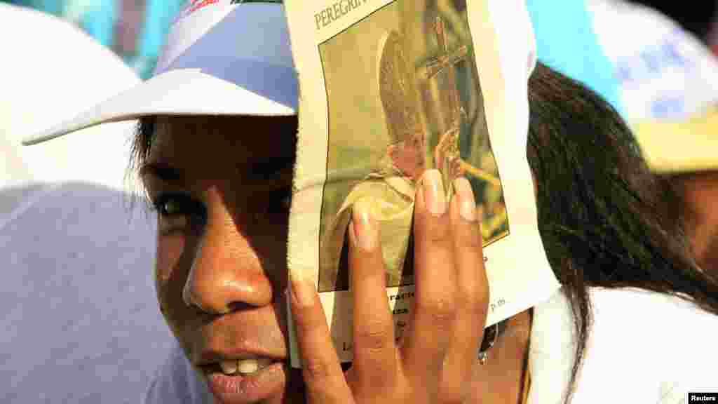 Женщина прикрывает лицо от солнца, ожидая выступления Папы Бенедикта XVI на площади Антонио Масео, Сантьяго-де-Куба