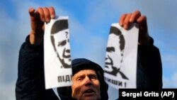 Demonstrant drži rastrgani portret tadašnjeg ukrajinskog predsjednika Viktora Janukoviča i uzvikuje "Kukavica!" na skupu 29. novembra.
