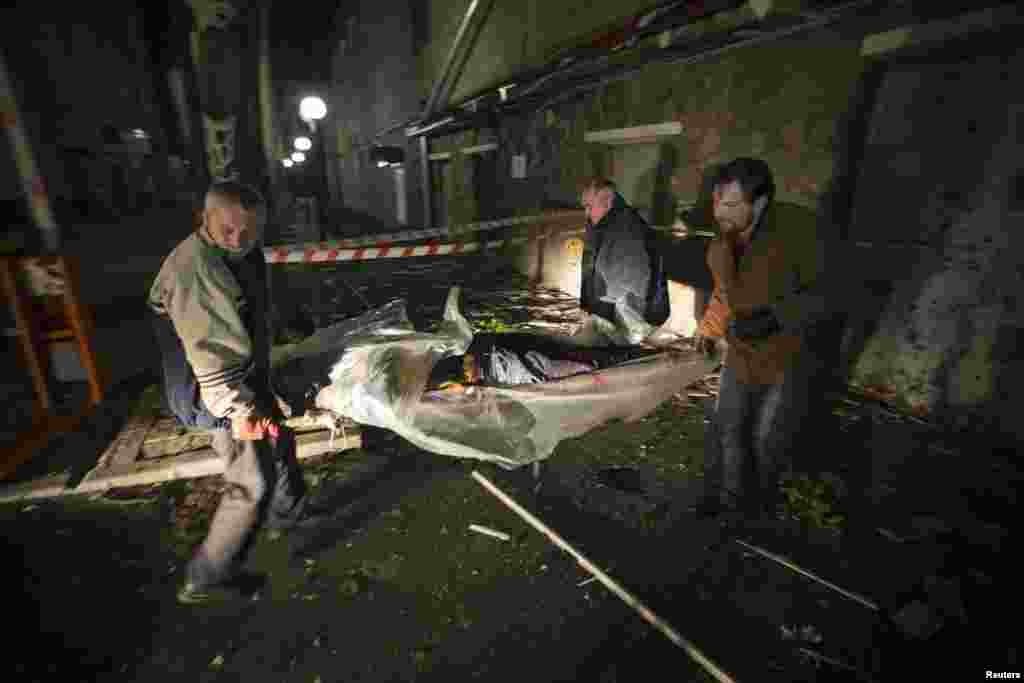 Люди несуть тіло загиблого внаслідок артобстрілу біля офісу Червоного Хреста в Донецьку, 2 жовтня 2014 року