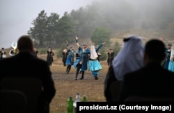 პრეზიდენტი ილჰამ ალიევი (მარცხნივ) 2025 წლის სექტემბერში შუშაში მოცეკვავეების გამოსვლას უყურებს.