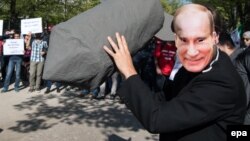 Человек в маске Путина с макетом бомбы перед российским посольством в Берлине во время демонстрации против действий России в Сирии