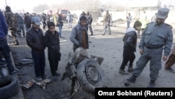 Policija i lokalno stanovništvo gleda u ostatke automobila na mjestu gdje se dogodio samoubilački napad u kojem je jedna osoba poginula a 13 ranjeno, 28. 12. 2015.