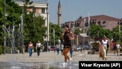 Një grua e re duke ecur pranë një shatërvani gjatë një dite të nxehtë vere në Prishtinë. Fotografi ilustruese nga arkivi