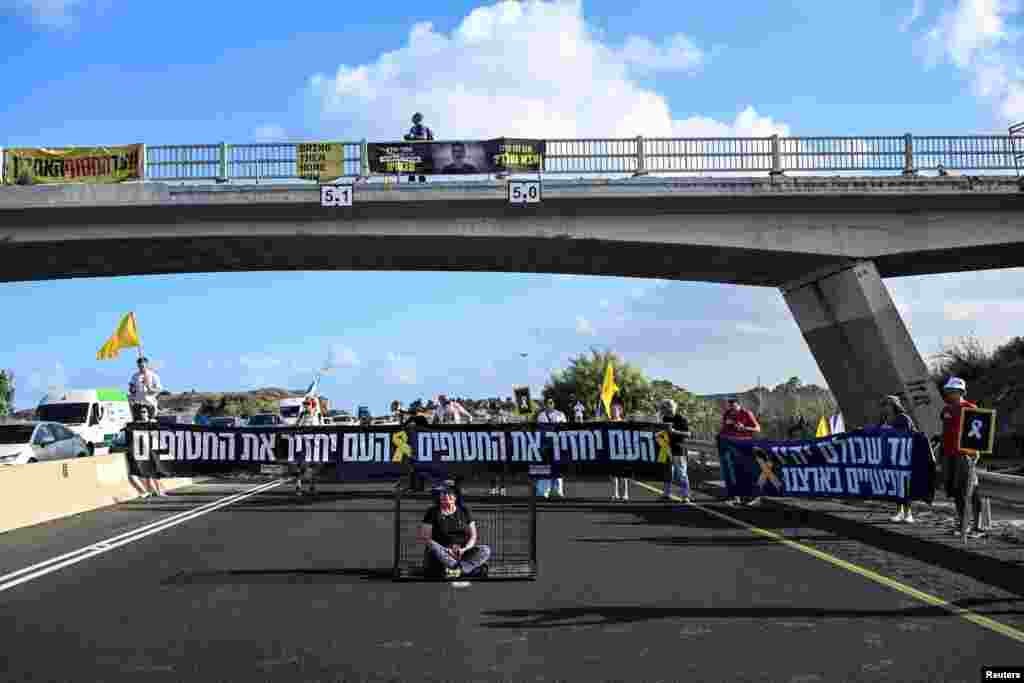 Demonstrant sjedi u kavezu, simbolično pozivajući na oslobađanje talaca, za vrijeme blokade glavne ceste tokom demonstracija blizu Habonima u Izraelu, 26. avgusta 2025. godine.