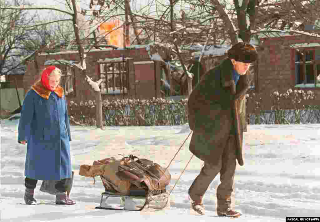 Пожилые супруги покидают Грозный со своими пожитками, уместившимися на санках. В городе нет света, газа, воды и еды. 24 января 1995 года  