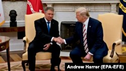 U.S. President Donald Trump (right) shakes hands with Romanian President Klaus Iohannis in the Oval Office of the White House in Washington, D.C., on August 20.