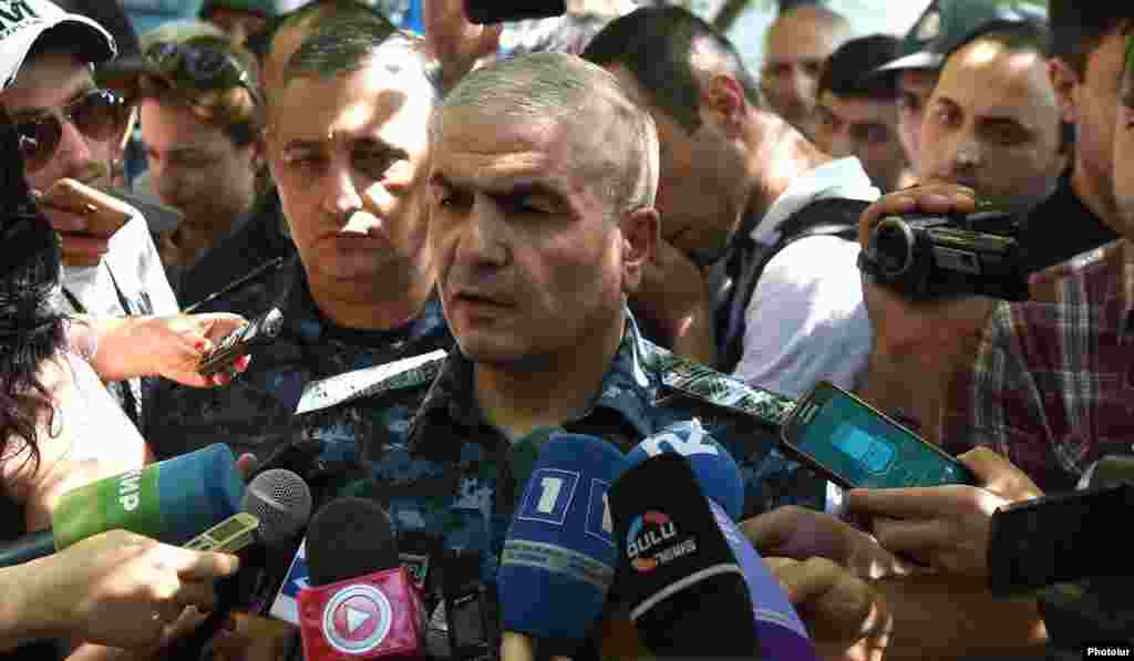 Заместитель начальника полиции Армении Унан Погосян беседует с журналистами возле захваченного здания полиции в Ереване.   