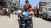 Un palestinian în cărucior cu rotile, purtându-și protezele, pleacă din calea noii ofensive israeliene, în orașul Gaza, pe 26 august. 