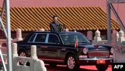 Predsjednik Kine Si Đinping se vozi kroz Peking stojeći u vozilu s otvorenim krovom tokom vojne parade 3. septembra 2015.