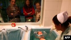 Kineska porodica gleda svoju bebu na medicinskom tretmanu u bolnici u Jilinu, mart 2018. godine
