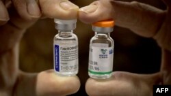 A health worker shows vials of Russian Sputnik V (left) and Chinese Sinopharm vaccines.