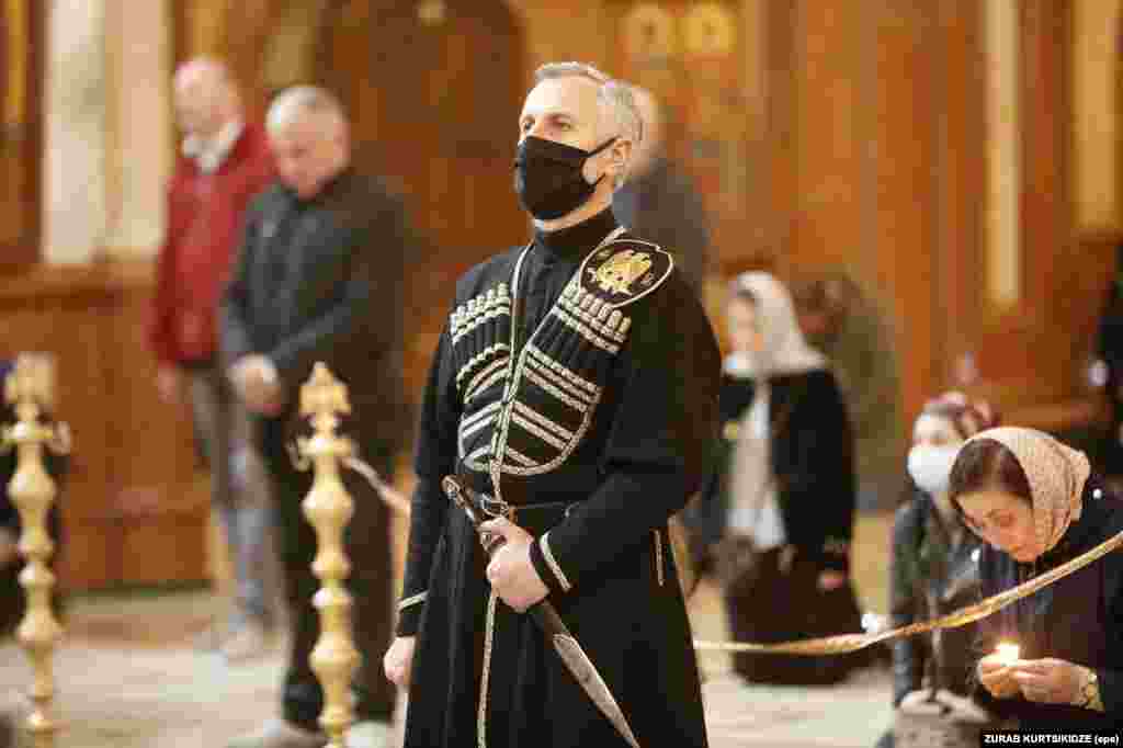 A Georgian man wears a mask that matches his traditional Caucasian clothing during a service in Tbilisi's Trinity Cathedral on April 16 as worshippers maintain physical distancing.