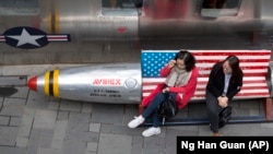 Китаянки перед магазином одежды на скамейке с флагом США, Пекин, 23 марта 2018