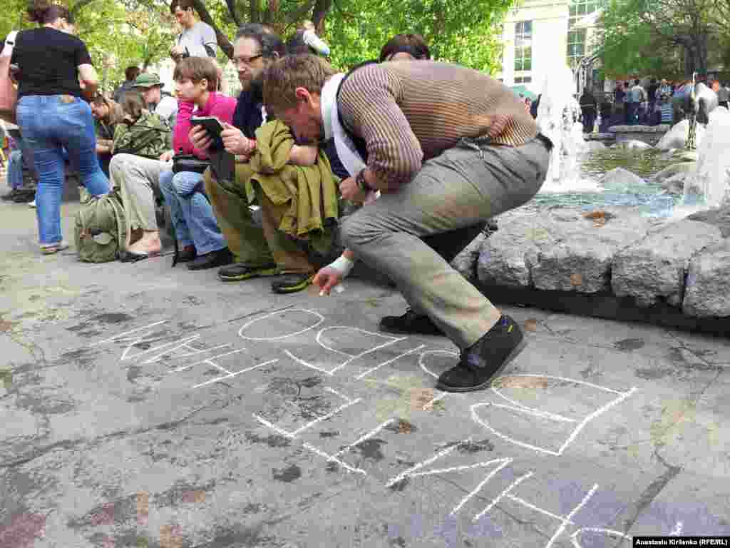 Парень, которому сегодня сломали палец в атозаке, пишет мелом на асфальте "Верните выборы"