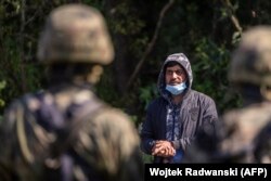 ჩიხში მოქცეული მიგრანტი პოლონელი სამხედრო მოსამსახურის უკან. თავდაცვის მინისტრმა, მარიუშ ბლაშჩაკმა, 23 აგვისტოს განაცხადა, რომ პოლონეთი აღმართავს ზღუდეს ბელარუსთან საზღვარზე და რომ იქ განლაგებული ჯარის რაოდენობა, რომელიც მიგრანტების ტალღას უმკლავდება, გაორმაგდება და 2000-ს მიაღწევს.