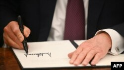 Američki predsjednik Donald Trump potpisuje izvršne naredbe u Ovalnoj kancelariji Bijele kuće u Washingtonu, 20. januara 2025. 