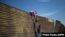Migranti prelaze ogradu na granici sa Meksikom
