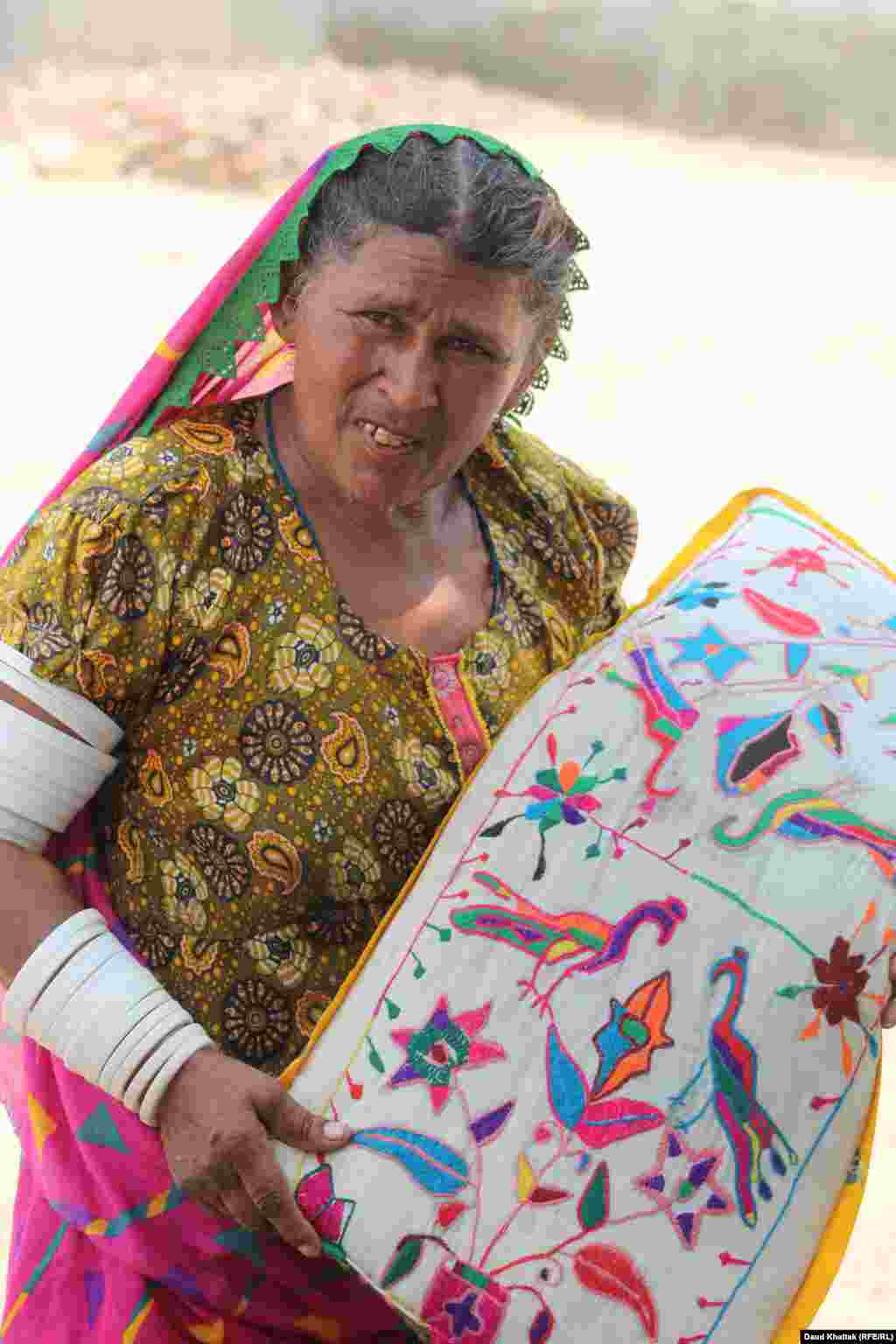 Kallan Bibi holds a handmade pillow case featuring Tharparkar&#39;s traditional embroidery.