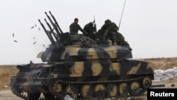 Government soldiers sit on a tank at the western gate of the town of Ajdabiya on March 16.