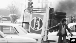 გადაყირავებული სატვირთო მანქანა პეპსის წარწერით იწვის თეირანის ცენტრში. 1978 წლის 27 დეკემბერს არეულობის შედეგად ირანის დედაქალაქი პარალიზებულია.