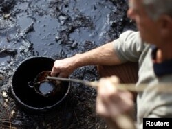 Hajro Bilalić prikuplja naftu u svom dvorištu kod Tuzle, oktobar 2011.