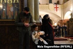 პატარა ბიჭი ხელს ითბობს სანთელზე.