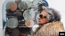 Atenta, 12 februarie 20210. O femeie trece pe lângă un poster pe care sunt trecute dobânzile pentru depozite bancare.