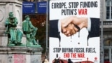 Активисты и представители СМИ возле открытого билборда с надписью "Европа, прекрати финансирование войны Путина. Прекратите покупать ископаемое топливо, завершите войну" у Европейского парламента в Брюсселе