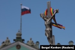 ჯვარცმაზე შებმული ცისარტყელას ფერებიანი ლენტი ერმიტაჟის თავზე, რუსეთის დროშის გვერდით.