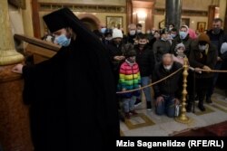 სასულიერო პირი და მრევლი სამების ეკლესიაში ნათლისღების დღესასწაულზე.