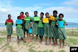 Copii de la școala Suango Mele pozând cu pancarte pro-mediu pe 24 iulie.