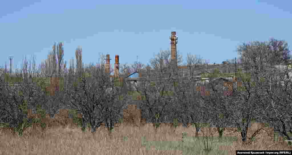 Заброшенный яблоневый сад на фоне труб винзавода в селе Почтовое. На заводе, принадлежащему выходцам из Днепра, делают вино торговой марки «Золотая амфора»