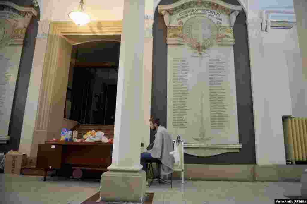 Student ogrnut ćebetom pored samog ulaza u Rektorat i stola sa hranom.&nbsp;