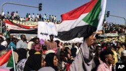 SUDAN -- Sudanese demonstrators march with national flags as they gather during a rally demanding a civilian body to lead the transition to democracy, outside the army headquarters in the Sudanese capital Khartoum on Saturday, April 13, 2019.