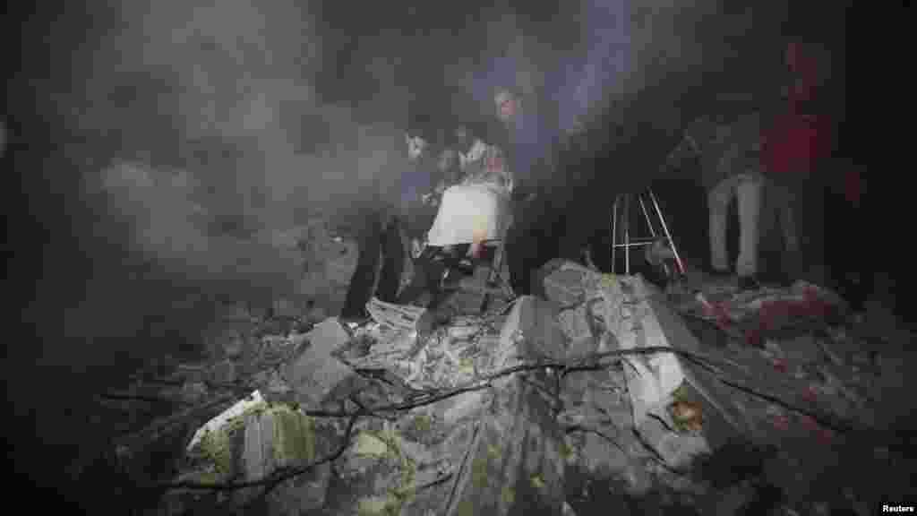 Палестинці виносять старшу жінку з руїн дому після ізраїльського удару в місті Газа, фото 14 листопада 2012 року