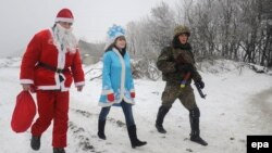 Волонтери переодягнені у костюми Діда Мороза та Снігуроньки разом з українським військовослужбовцем біля Лисичанська. Січень 2015 року. Ілюстраційне фото