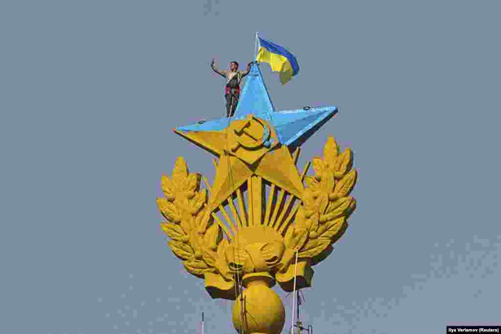 Працівник альпініст робить «селфі» поруч з перефарбованою радянською зіркою та українським прапором, Москва, 20 серпня 2014 року