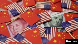 Cеред прапорів США та Китаю банкнота американського долара із зображенням одного з батьків-засновників США Бенджаміна Франкліна та банкнота китайського юаня із зображенням покійного голови КНР Мао Цзедуна. Фото зроблене 20 травня 2019 року