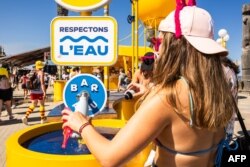 O participantă la un festival de muzică din sudul Franței umple sticlă cu apă, duminică, 29 iunie.